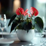 A sophisticated red anthurium centerpiece on a modern dining table, with soft lighting and blurred glasses in the background.